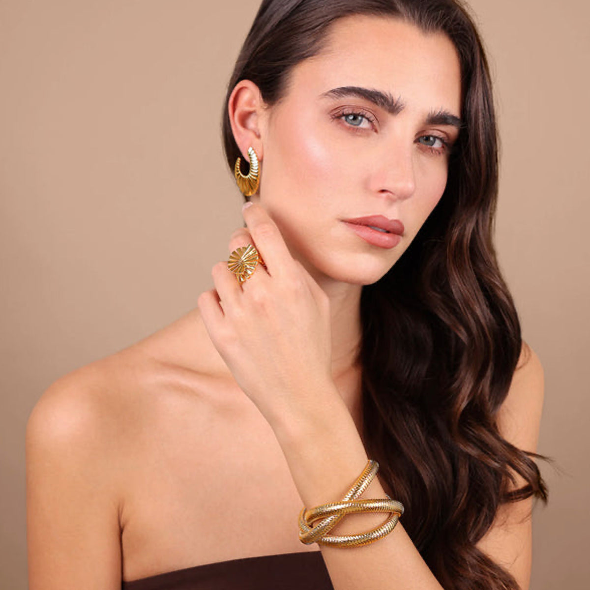 Model showcasing ETRUSCA JEWELS JEWELRY Mod. WSET00869.YG with gold earrings, ring, and bracelet on a beige background.