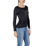 Woman wearing Guess Black Viscose Sportswear sweater with triangle logo, standing against white background.
