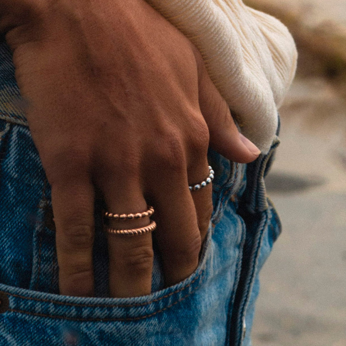 Hand wearing rings by AN JEWELS JEWELRY Mod. AR.R2NS04R-8, stylishly paired with denim jeans, close-up view.
