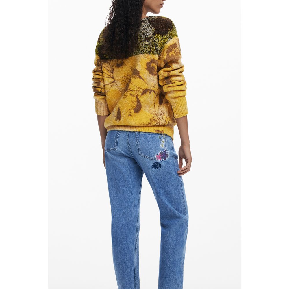 Back view of model wearing Desigual Yellow Wool Women Sweater with vibrant pattern and floral design, paired with embroidered jeans.