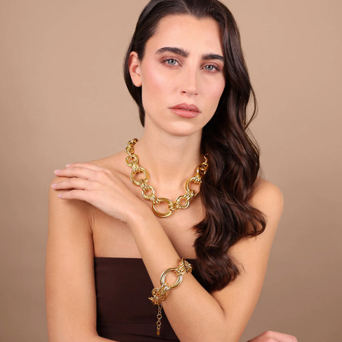 Model wearing ETRUSCA JEWELS JEWELRY Mod. WSET00893.YG necklace and bracelet set on a beige background