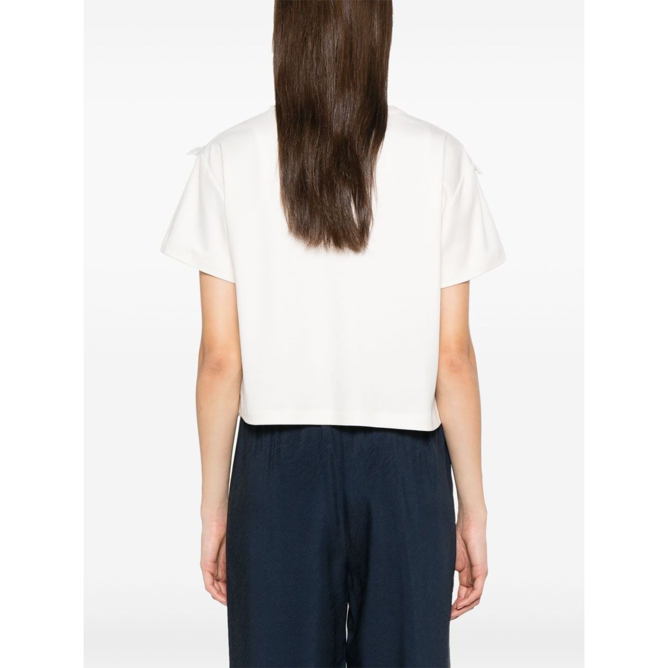 Back view of model wearing white Emporio Armani T-shirt with fringes, short sleeves, crew neck, and rear button fastening.