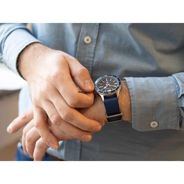 Gent's wrist wearing NAUTICA Mod. NAPABS904 quartz analog watch with mineral dial, 5 ATM water resistance, and official packaging.