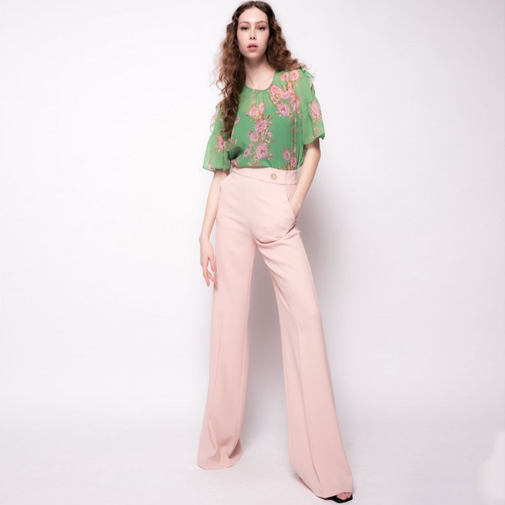 Model wearing PINKO Pink Polyester Women's Trouser with high waist and offset leg cut, paired with a green floral top.