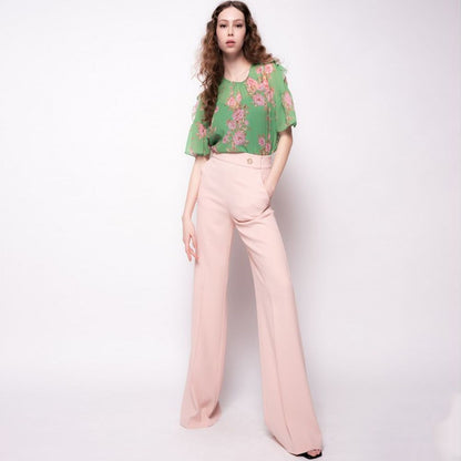 Model wearing PINKO Pink Polyester Women's Trouser with high waist and offset leg cut, paired with a green floral top.